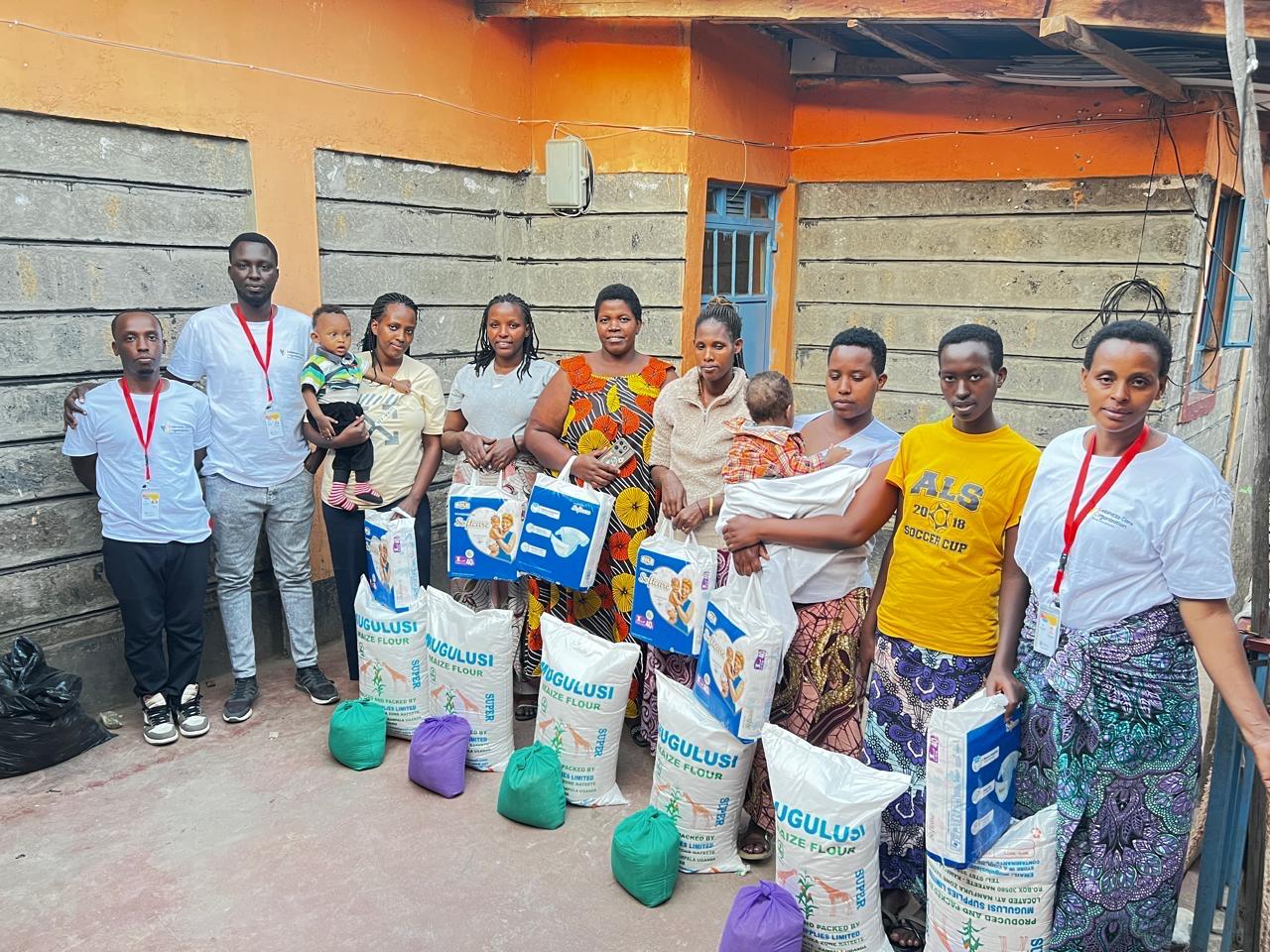 Sebineza Care Organization distributing food supplies and maternal care items to refugee women holding newborn babies in Kitengela Kenya.